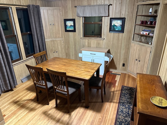 dining space with wood walls and light wood-type flooring