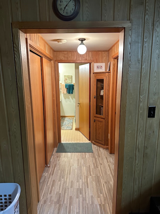 hall with wood walls and light hardwood / wood-style flooring