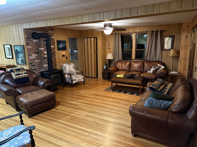 9516 State Highway M64, Marenisco, MI 49947 - living room with a wood stove, wooden walls, hardwood / wood-style floors, and a ceiling fan