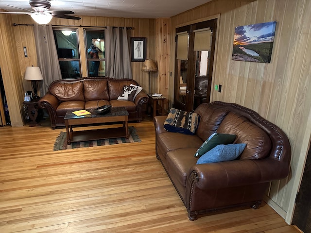 living room featuring wood walls, light hardwood / wood-style flooring, and ceiling fan