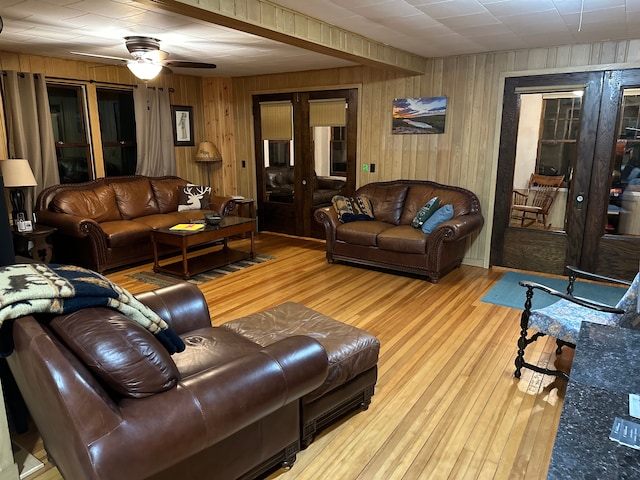 living room featuring light hardwood / wood-style floors, ceiling fan, and wood walls