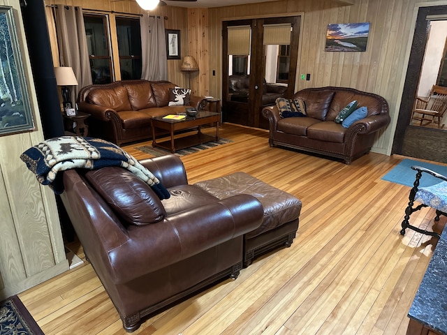 living room featuring ceiling fan, wooden walls, and light hardwood / wood-style flooring