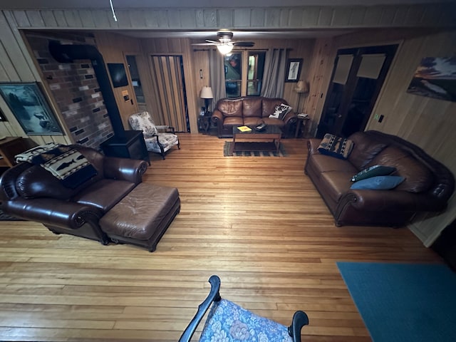 living room with wooden walls, ceiling fan, and hardwood / wood-style flooring