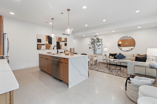 kitchen with pendant lighting, light stone counters, sink, and stainless steel appliances