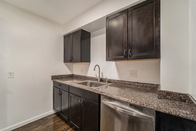 kitchen featuring dark brown cabinetry, sink, stainless steel dishwasher, dark hardwood / wood-style floors, and dark stone counters