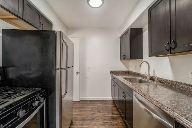 kitchen with sink, dark hardwood / wood-style floors, dark stone counters, dark brown cabinets, and black appliances