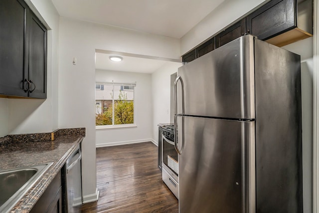 kitchen featuring dark hardwood / wood-style floors, dark stone countertops, sink, and appliances with stainless steel finishes