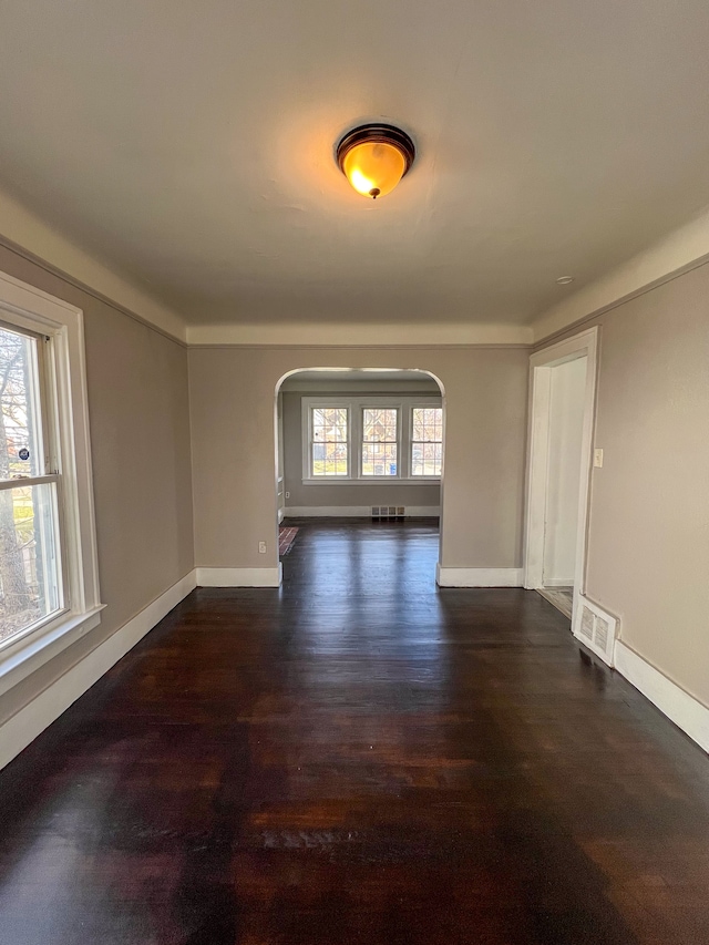 empty room featuring plenty of natural light and dark hardwood / wood-style flooring