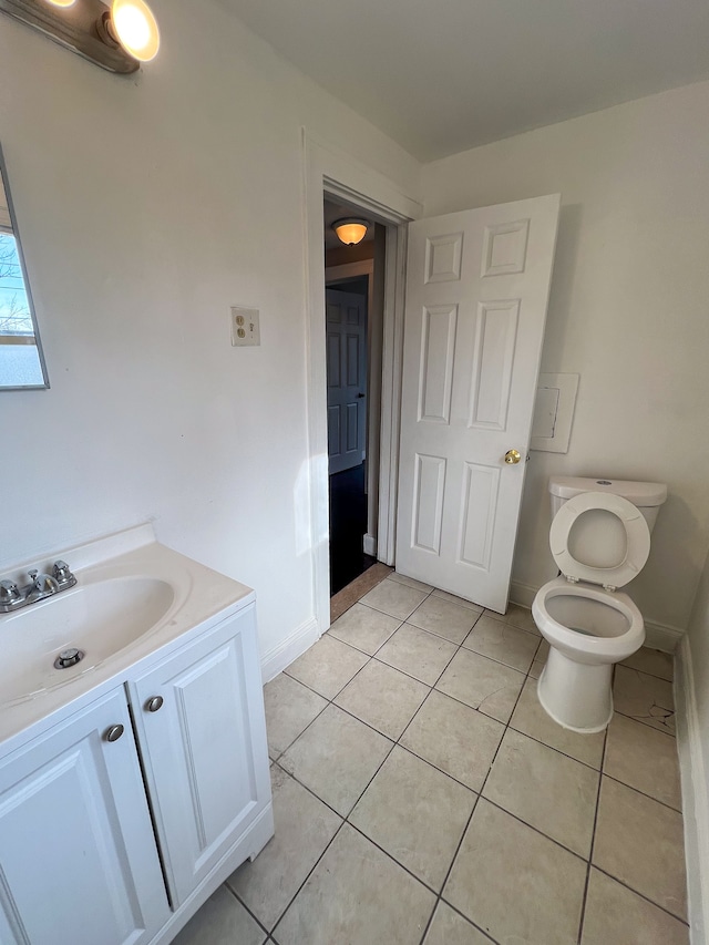 bathroom with toilet, vanity, and tile patterned floors