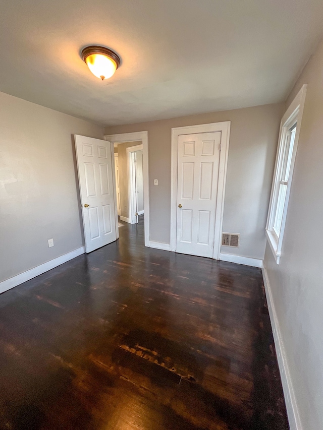 unfurnished bedroom with dark hardwood / wood-style flooring