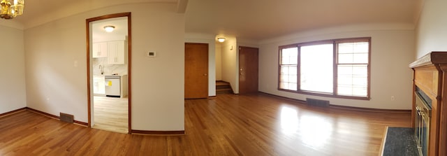 unfurnished living room featuring a notable chandelier and wood-type flooring