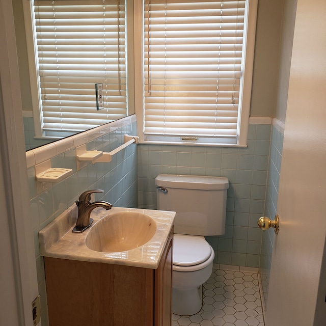 bathroom with toilet, vanity, tile patterned floors, and tile walls