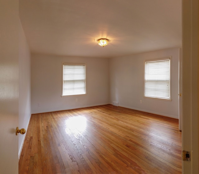 spare room featuring a healthy amount of sunlight and light hardwood / wood-style floors