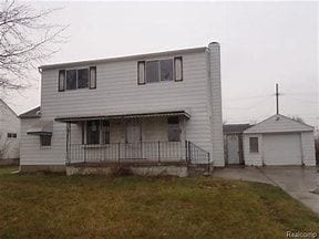 view of front of property featuring an outbuilding, a front lawn, a porch, and a garage