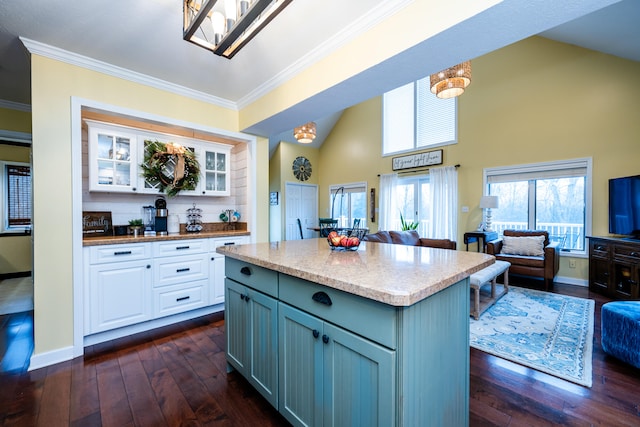 kitchen with a center island, high vaulted ceiling, dark hardwood / wood-style floors, ornamental molding, and white cabinetry