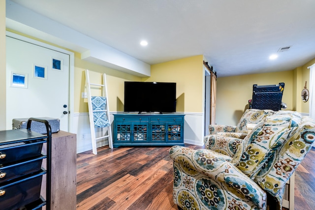 living room with a barn door and dark hardwood / wood-style flooring