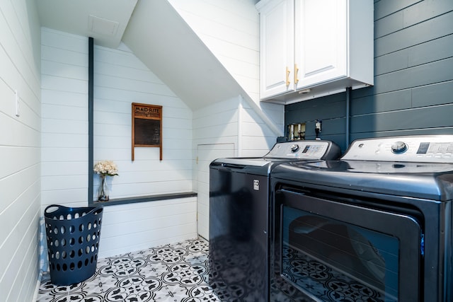 washroom with cabinets, washing machine and dryer, and wood walls