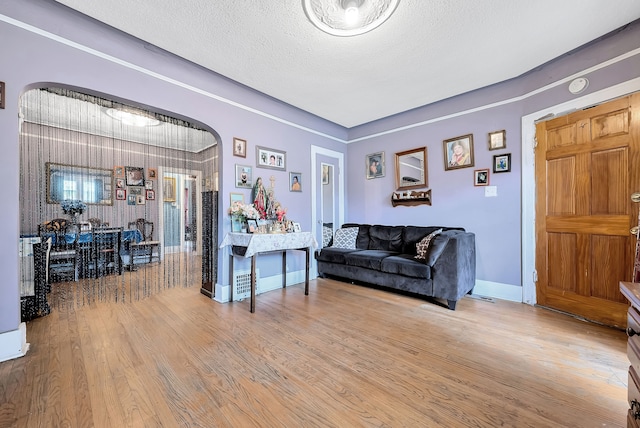 776 Woodmere St, Detroit, MI 48209 - living room with arched walkways, wood finished floors, baseboards, and a textured ceiling