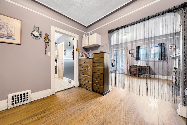 interior space with white cabinets, a textured ceiling, and light hardwood / wood-style flooring