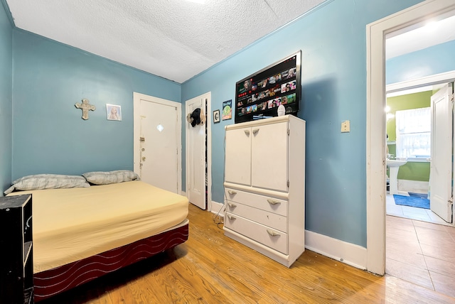 bedroom with a textured ceiling and light wood-type flooring