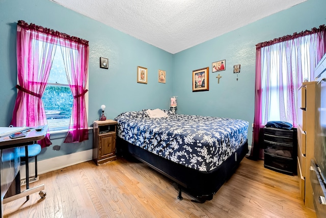 bedroom with multiple windows, light hardwood / wood-style flooring, and a textured ceiling