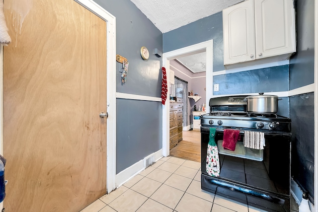 776 Woodmere St, Detroit, MI 48209 - kitchen featuring black range with gas cooktop, white cabinetry, a textured ceiling, light tile patterned floors, and baseboards