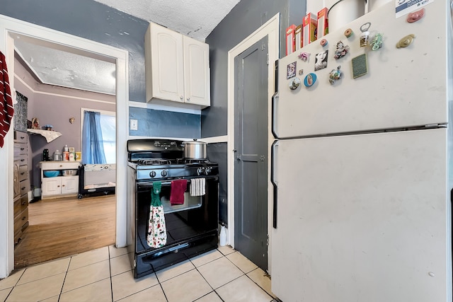 kitchen featuring light tile patterned flooring, white refrigerator, black range with gas cooktop, a textured ceiling, and white cabinets