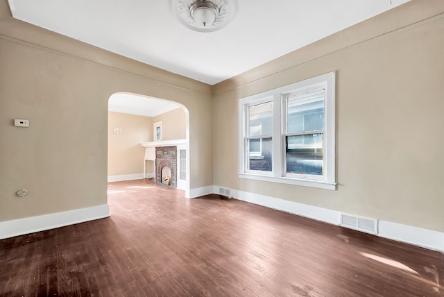 776 Woodmere St, Detroit, MI 48209 - spare room with arched walkways, wood-type flooring, baseboards, and a fireplace with flush hearth