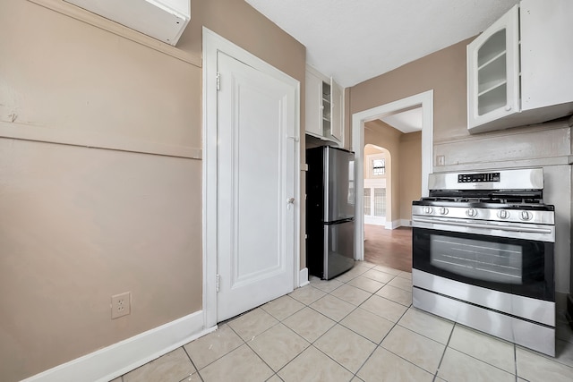 776 Woodmere St, Detroit, MI 48209 - kitchen with stainless steel appliances, white cabinets, light tile patterned floors, glass insert cabinets, and baseboards