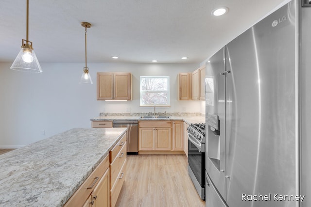 kitchen with appliances with stainless steel finishes, sink, light brown cabinets, light hardwood / wood-style flooring, and hanging light fixtures