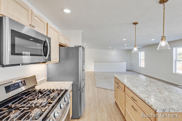 kitchen featuring light brown cabinets, hanging light fixtures, light hardwood / wood-style flooring, appliances with stainless steel finishes, and light stone counters