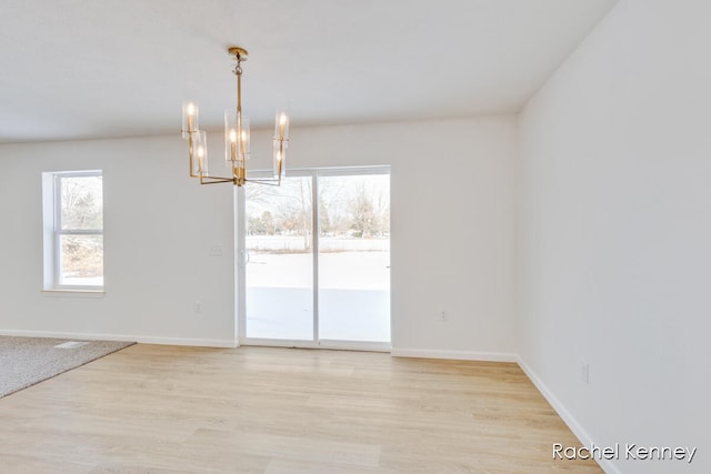 unfurnished dining area featuring an inviting chandelier and light hardwood / wood-style flooring