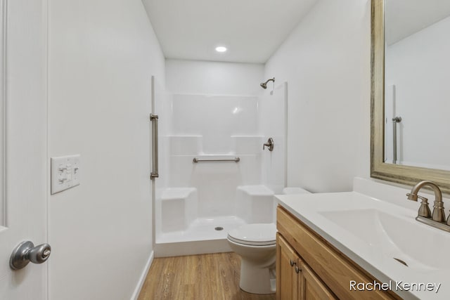 bathroom with hardwood / wood-style floors, vanity, toilet, and walk in shower