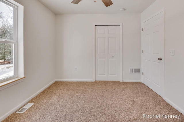 unfurnished bedroom featuring ceiling fan, light carpet, and multiple windows