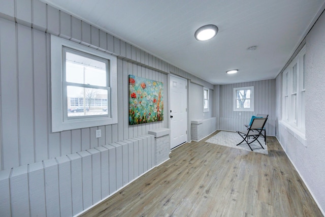 foyer entrance featuring radiator heating unit, light wood-type flooring, and wood walls