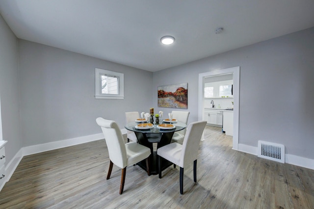 dining room featuring sink, a healthy amount of sunlight, and light wood-type flooring