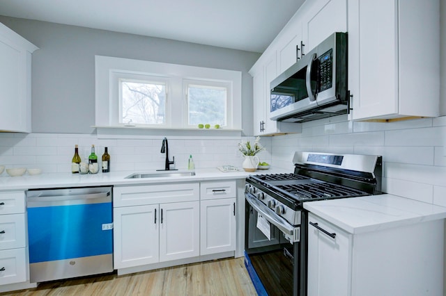 kitchen with sink, white cabinets, stainless steel appliances, and light wood-type flooring