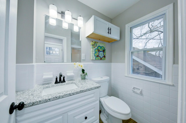 bathroom featuring vanity, toilet, and tile walls