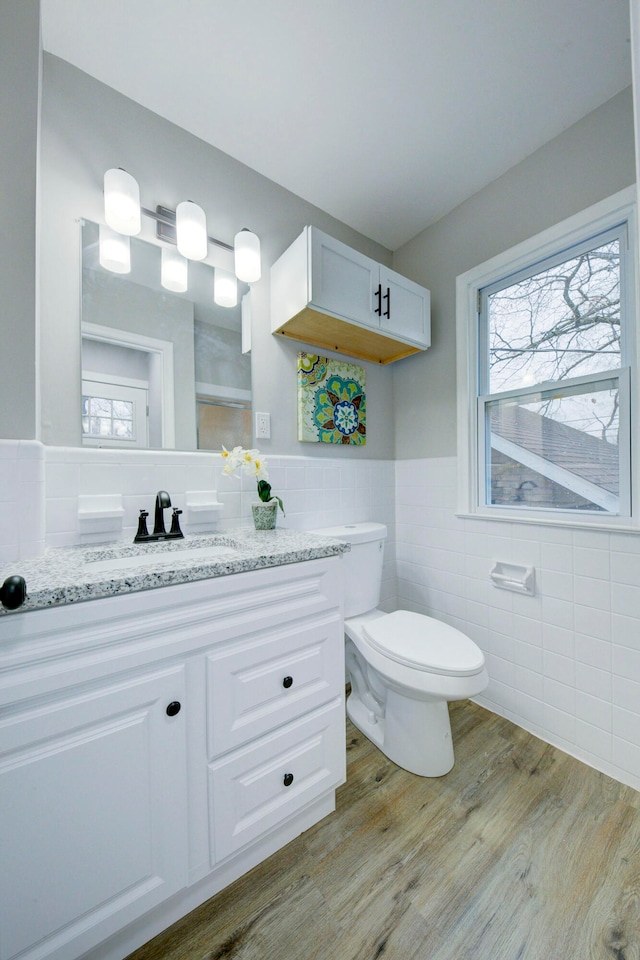 bathroom with hardwood / wood-style floors, vanity, tile walls, and toilet