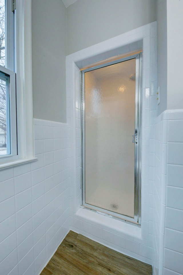 bathroom with hardwood / wood-style flooring, an enclosed shower, and tile walls