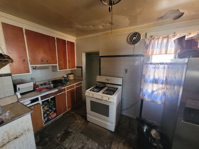 kitchen featuring white gas range oven, tile walls, and sink