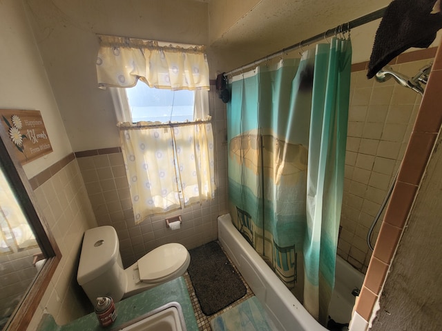 bathroom with shower / bath combo, toilet, and tile walls