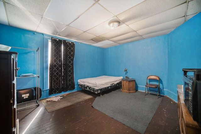 bedroom with a paneled ceiling and dark hardwood / wood-style floors