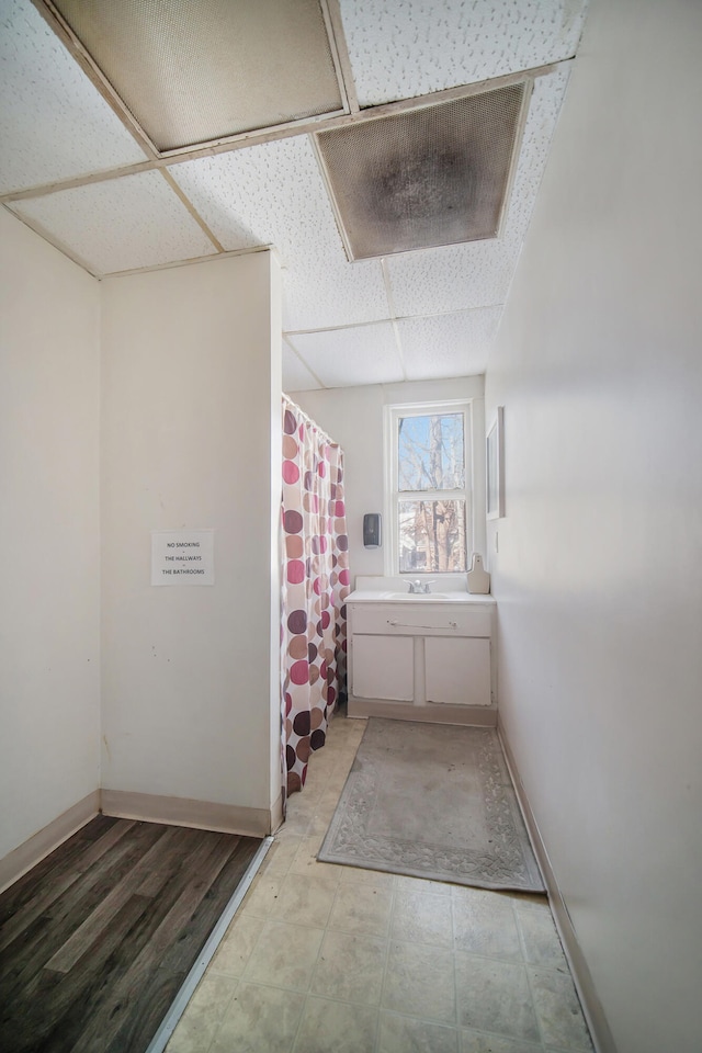 bathroom featuring a shower with shower curtain, a drop ceiling, and vanity