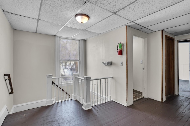 hall featuring a paneled ceiling and dark hardwood / wood-style floors