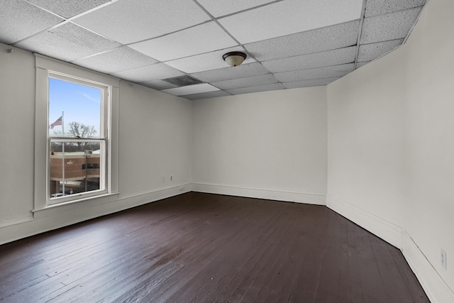 spare room featuring dark hardwood / wood-style floors and a drop ceiling