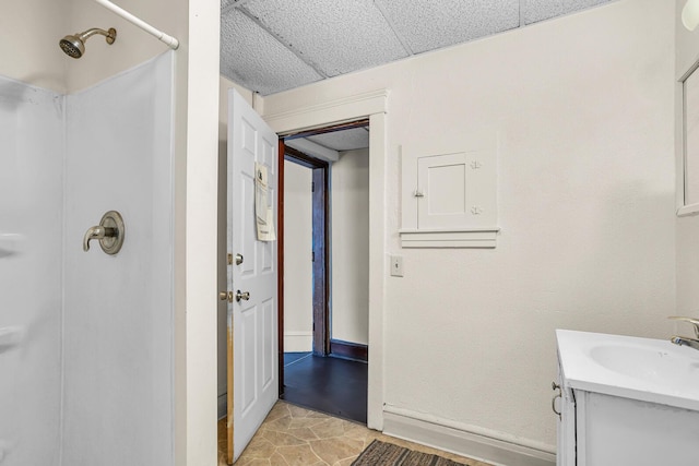 bathroom featuring a shower, vanity, and a drop ceiling