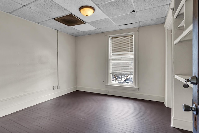 empty room featuring a drop ceiling and dark wood-type flooring