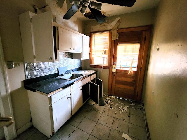 kitchen with backsplash, white cabinetry, sink, and ceiling fan