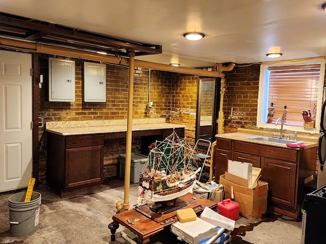 interior space featuring dark brown cabinets, brick wall, sink, and electric panel